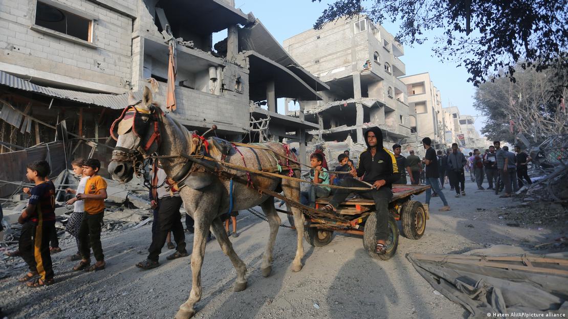 A man drives his horse-drawn cart past buildings destroyed in the Israeli bombardment of Gaza