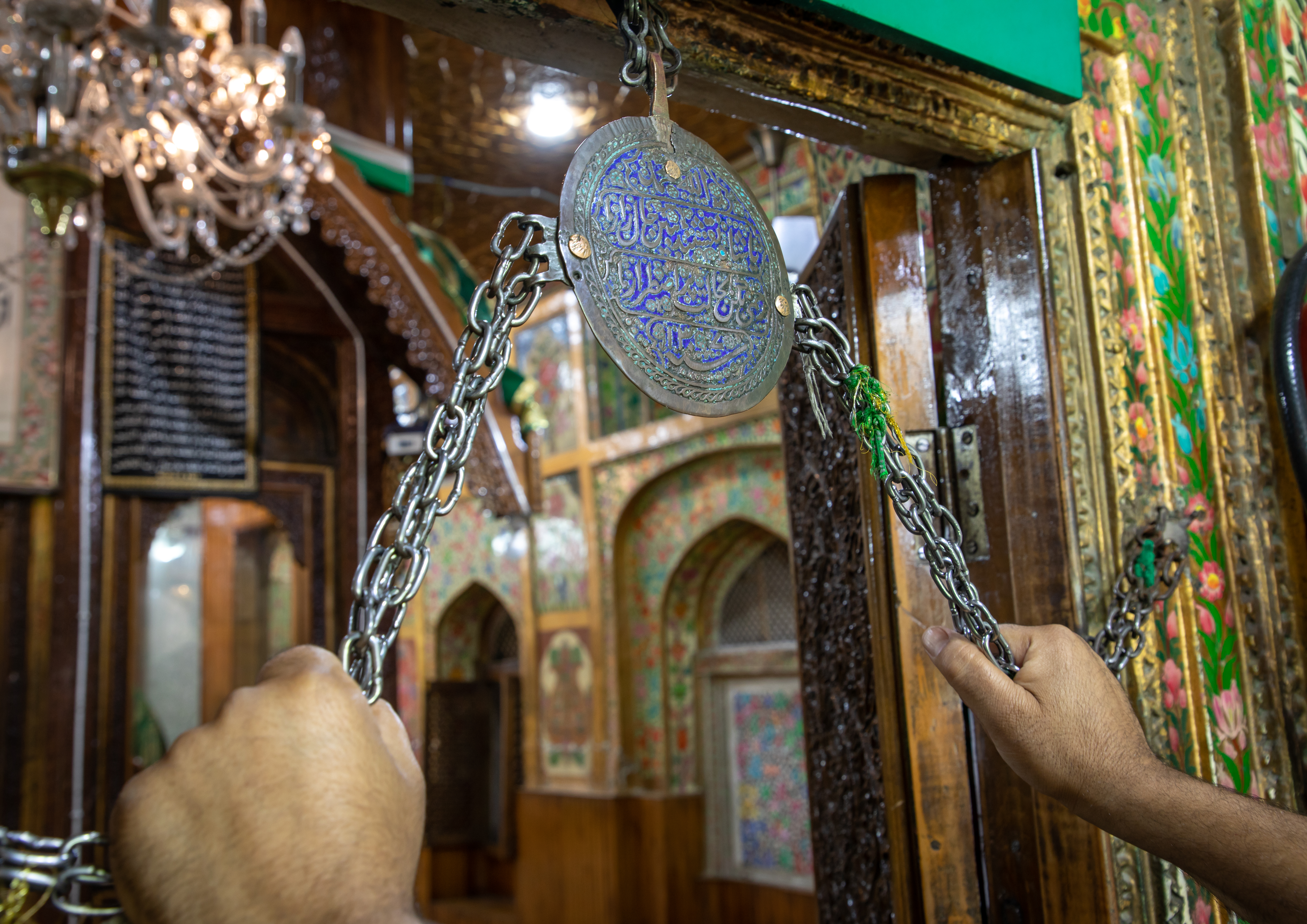 A man grasps chains as a sign of devotion on entering a Sufi shrine