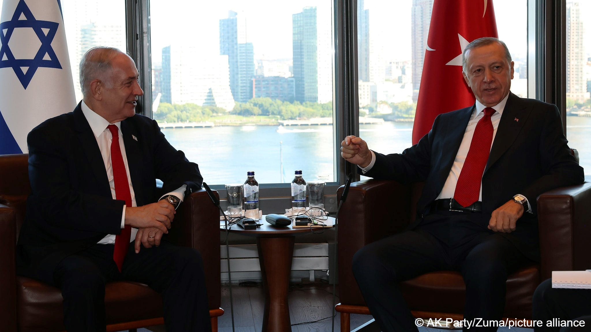 Turkish President Recep Tayyip Erdogan (right) speaks while Israeli Prime Minister Benjamin Netanyahu (left) smiles at him, both men are sitting in leather armchairs, the New York skyline can be seen through the window behind them, Turkish House, New York, USA, 19 September 2023 