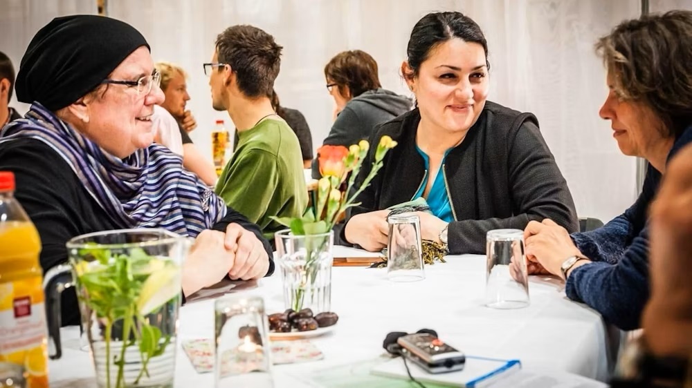 صورة من: Lutz Jäkel - رابعة مولَر (على اليسار) أثناء تناول الإفطار في شهر رمضان؛ وتجلس م عها على الطاولة أيضًا لمياء قدور (في الوسط).Rabeya Müller (links) während eines Iftar-Essens. Mit am Tisch: Lamya Kaddor (Mitte). 