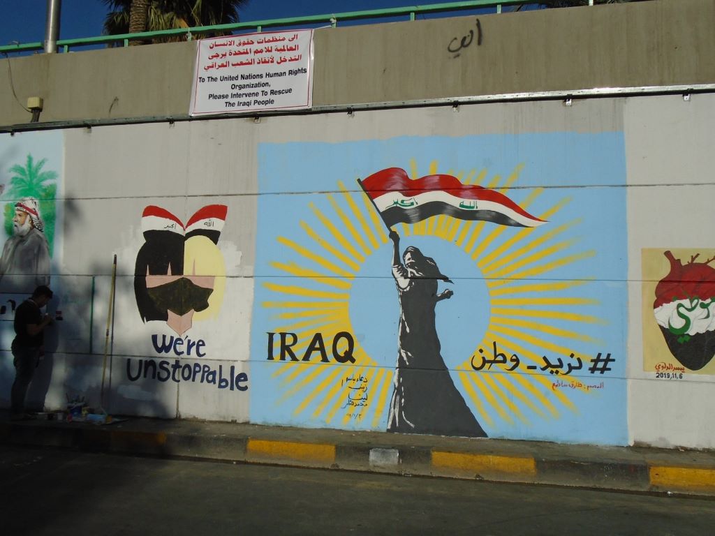 Feminist graffiti featuring the words "we're unstoppable" and "Iraq" and the Irawi flag n a wall in Iraq 