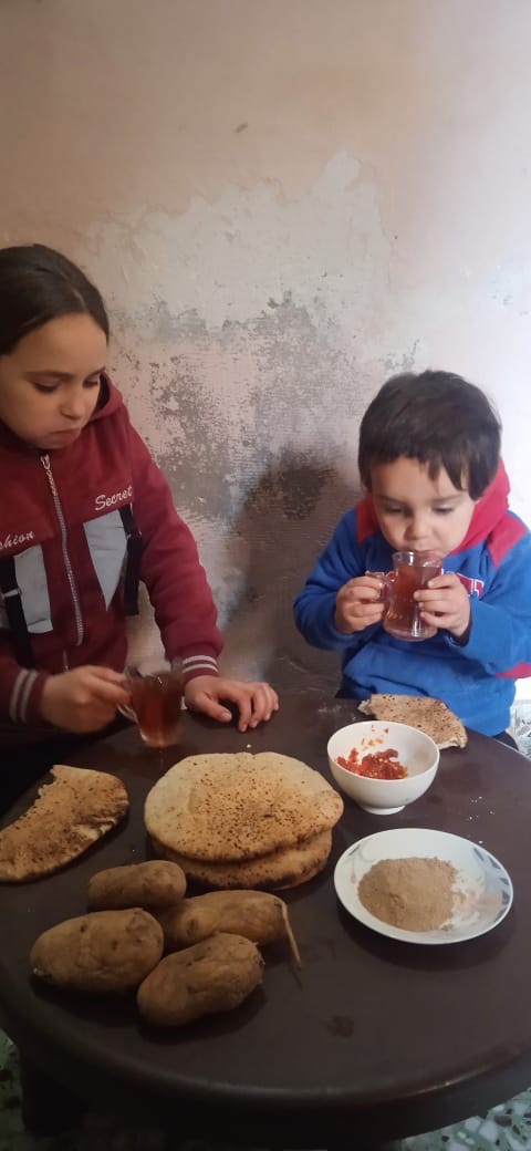 Two of Ibrahim Kharabishi's children eating a scant lunch of a couple of potatoes