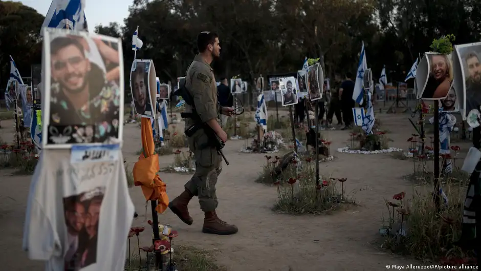 An Israeli soldier stands among posts bearing the images of Hamas victims at the site of the Nova music festival in Re'im