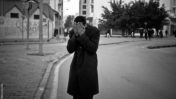 Man holding his head in his hands on a a Tunis street (photo: Selim Harbi)