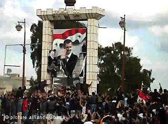 Demonstranten zerstören ein Plakat mit dem Porträt Baschar al-Assads in Daraa; Foto: picture alliance/abaca 