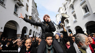 Young woman with a megaphone and protesters during an anti-regime demonstration in Rabat in February (photo: picture alliance/dpa)