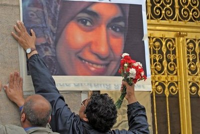 Two men affix a picture of Marwa El-Sherbiny on a wall (photo: dpa)