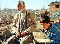 Ahmet Kaya, a 76-year-old Turkish Kurd, enjoys the sun as his grandson Feyyaz Kaya, 8, recites the Muslim's holy book or Koran in the ghetto outside of Diyarbakir