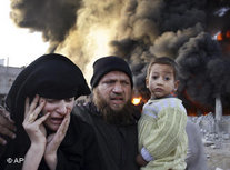 A Palestinian family rushes past a burning building after an Israeli missile strike in the Rafah refugee camp, southern Gaza Strip, Sunday, 28 December 2008 (photo: AP)
