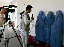 Afghan unidentified women clad in burqas are interviewed by a TV crew member (photo: AP)