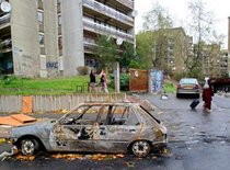 Clichy-sous-Bois residents walk past the wreckage of a burnt car, photo: AP