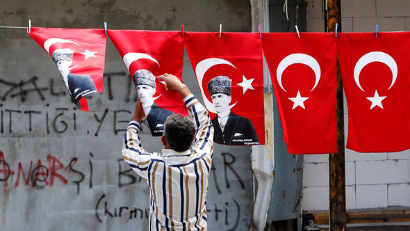 متظاهر يُعَلِّق العلم التركي مع صورة أتاتورك في الشارع. رويترز