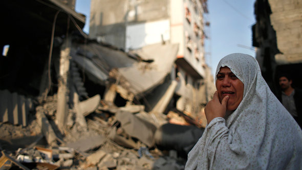 Eine palästinensische Frau steht vor ihrem zerstörten Haus in Gaza-Stadt; Foto: Reuters/Mohammed Salem