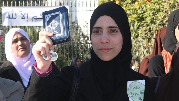 Tunesische Islamistin mit einem Aufkleber: Ja zur Scharia und einer Ausgabe des Korans in der Hand, Foto: DW