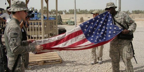 American soldiers fold the US flag on their military base in Iraq (photo: dpa)