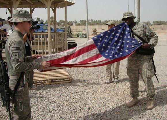 US-Soldaten im Irak falten die amerikanische Flagge auf ihrer Militärbasis im Irak zusammen; Foto: dpa