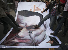 Jubelnde Demonstranten treten auf ein Mubarak-Plakat auf dem Tahrir-Platz in Kairo; Foto: AP
