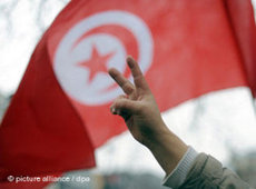 Demonstrant in Tunis formt die Hand zum Victory-Zeichen vor einer tunesischen Fahne; Foto: dpa 