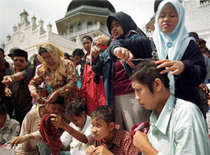 Acehnese women cut hair of four women suspected as prostitutes in front of Baiturrahman Mosque in the provincial capital of Banda Aceh, Aceh, Indonesia Sunday, 5 December 1999. Islamic law now is implemented by Muslim-affiliated separatists in the violence-wrecked region as they step up their campaign to break away from Indonesia (photo: AP)