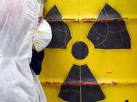 Mann in Schutzkleidung vor Fass mit radioaktivem Inhalt; Foto: dpa