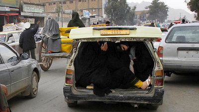 Eine Frau versteckt sich im Kofferraum eines Autos; Foto: DW
