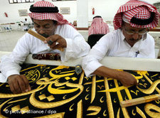 Saudi-arabische Männer weben Koran-Verse in ein Tuch; Foto: dpa
