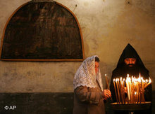 An Armenian Orthodox priest and a worshipper light candles following the Armenian Christmas Eve procession in the Church of the Nativity, traditionally believed to be the birthplace of Jesus Christ, in the West Bank town of Bethlehem, 18 January 2007 (photo: AP)