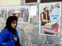 An Afghan woman passes by a poster encouraging to take part in the poll on the new constitution (photo: AP)