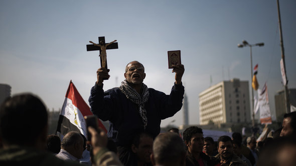 Auf einer Demonstration gegen die Macherweiterung Mursis hält ein Mann Koran und Kreuz in die Höhe, Tahrir-Platz in Kairo, 30. November; Foto: AFP Photo/Gianluigi Guercia