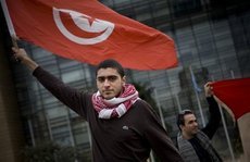 متظاهر تونسي ضد نظام بن علي يحمل علم بلاده. الصورة: AP