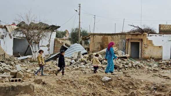 Syrische Zivilisten in einem zerstörten Dorf; Foto: DW/A. Stahl