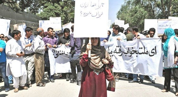 An Afghan woman, holding a placard which reads 'why just women are victims?', marches during a protest against the recent public execution of a young woman for alleged adultery, in Kabul on July 11, 2012. Dozens of Afghan women's rights activists took to the streets July 11 to protest the recent public execution of a young woman for alleged adultery, which was captured in ahorrific video (photo: AFP/Getty Images)
