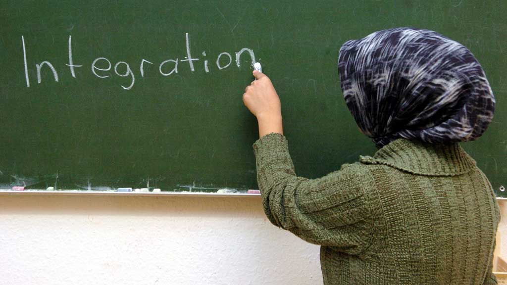 Eine türkische Frau schreibt im Schulungsraum der interkulturellen Frauenbegegnungsstätte "verikom" in Hamburg-Wilhelmsburg das Wort "Integration" an die Tafel; Foto: dpa/picture-alliance
