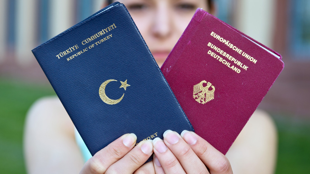 Eine junge Studentin hält ihren deutschen und türkischen Pass hoch.