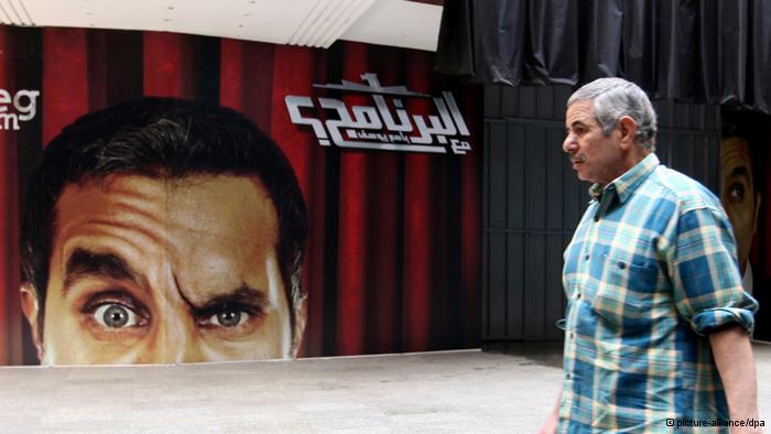 Mann in Kairo passiert Werbeplakat des Satirikers Bassem Youssef; Foto: dpa/picture-alliance