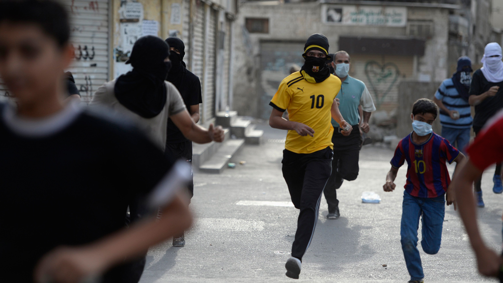 Protesters run for cover from tear-gas fired by riot-police during clashes in the village of Jidhafs, west of Manama, April 20, 2013 (photo: Reuters)