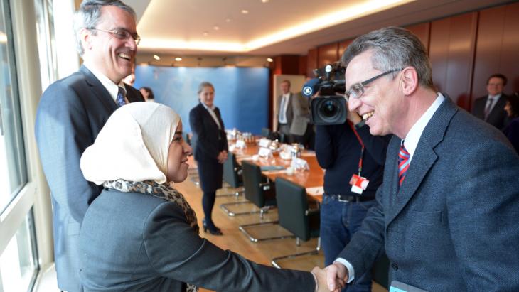 Thomas de Maizière greets a Muslim woman (photo: dpa/picture-alliance)