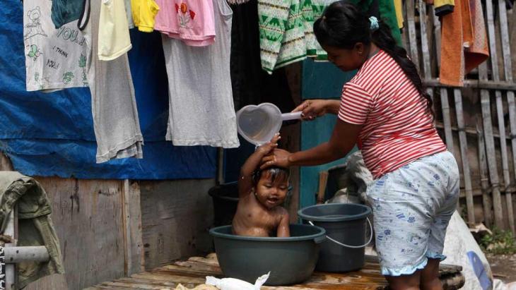 A woman washes her child outside her home in a slum in the Indonesian capital, Jakarta (Photo: AP)