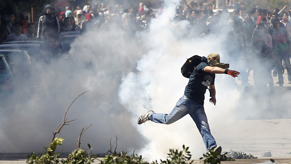 A supporter of the Muslim Brotherhood throws back a tear gas canister launched earlier by riot police during clashes outside Ain Shams University near Egypt's Defence Ministry headquarters in Cairo, 27 March 2014 (photo: Reuters)