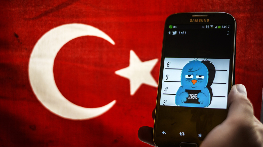 A picture representing a mug shot of the blue Twitter bird seen on a smartphone display in front of a Turkish flag on 26 March 2014 in Istanbul (photo: Ozan Kose/AFP/Getty Images)