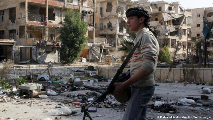 Junger Kämpfer vor zerstörter Häuserkulisse in Syrien; Foto: AFP/Getty Images