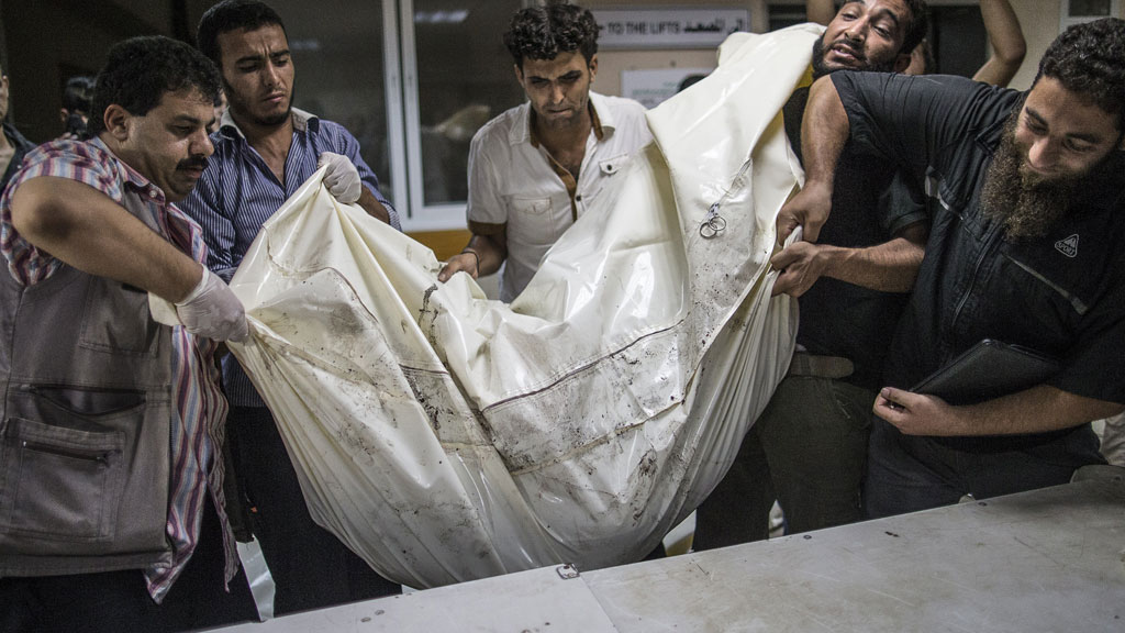 Palestinian volunteers at al-Shifa Hospital in Gaza lift a body bag (photo: Marco Longari/AFP/Getty Images)