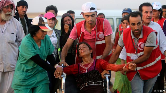 Mitarbeiter des Roten Halbmondes helfen einer jesidischen Frau: Foto: Reuters