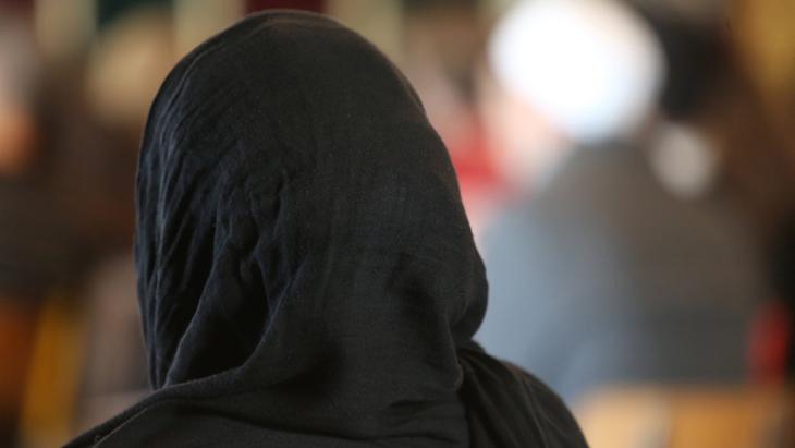 A woman wearing a black headscarf photographed from behind (photo: picture-alliance/Godong)