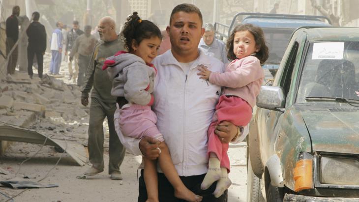 A man carries two children from the ruins of a house in Idlib after a barrel bomb attack orchestrated by the Syrian regime (photo: Reuters/Ammar Abdullah)