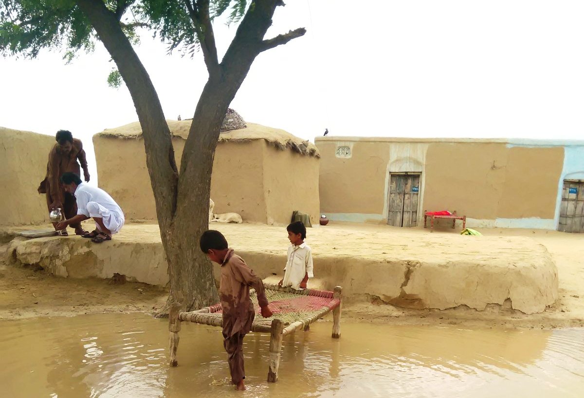 Kinder spielen in einer großen Wasserpfütze. Foto: Usman Mahar