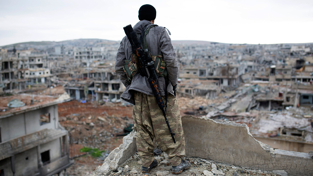 A Krudish sniper surveys the devastation of Kobani (photo: picture alliance/AP)