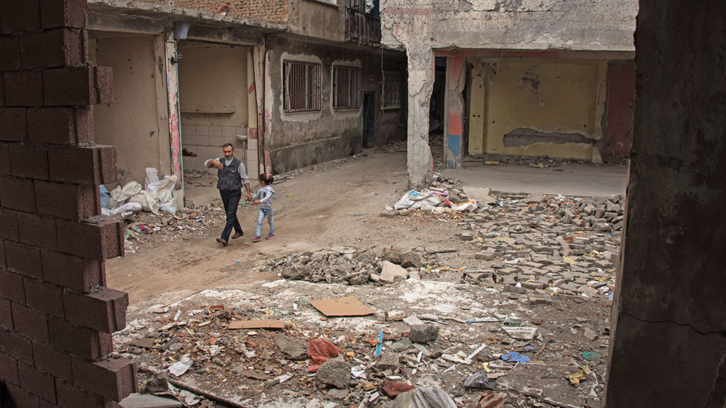 Mann mit Kind geht zwischen Trümmern im Bezirk Sur in Diyarbakir; Foto: DW