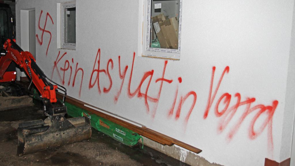 Der Schriftzug "Kein Asylant in Vorra" steht am 12.12.2014 in Vorra (Landkreis Nürnberger Land) an einer Hauswand. In drei als Flüchtlingsunterkunft vorgesehenen Gebäuden hatte es in der Nacht zu Freitag gebrannt; Foto: picture-alliance/dpa/ToMa