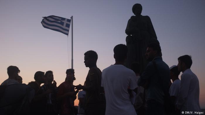 Flüchtlinge vor griechischer Fahne auf Lesbos; Foto: DW/Vincent Haiges